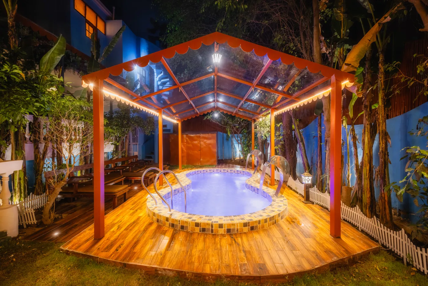 Plunge pool under a lit wooden pergola at night